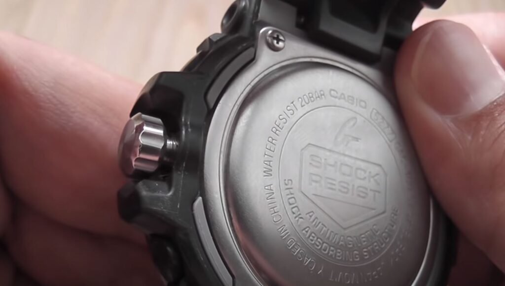 back stainless case of g shock watch with water in it thumb holding it